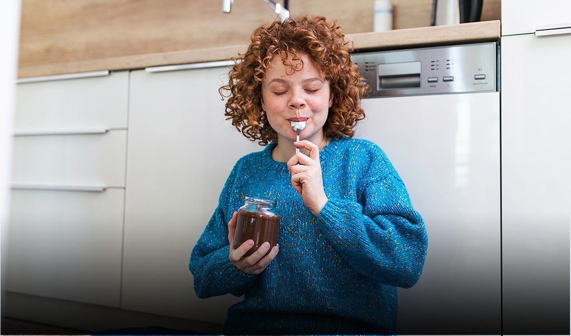 Eine Frau isst mit geschlossenen Augen einen Löffel Marmelade